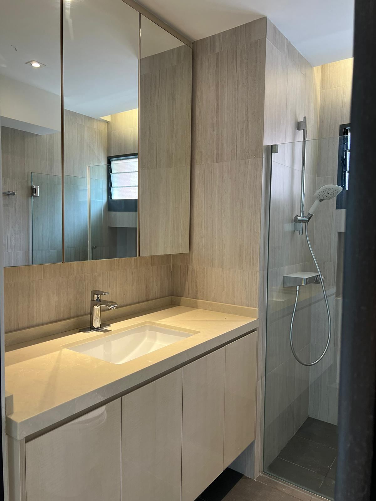 The vanity and shower with pale stone-look tiles and timber-look cabinets.
