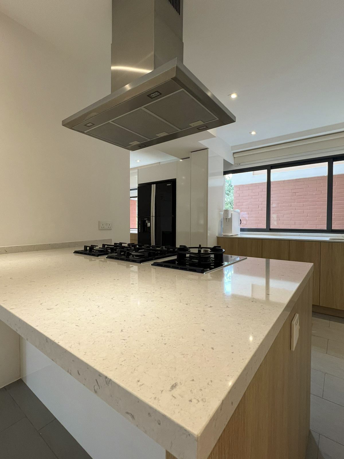 The kitchen island with a speckled stone worktop and hob under the hood.