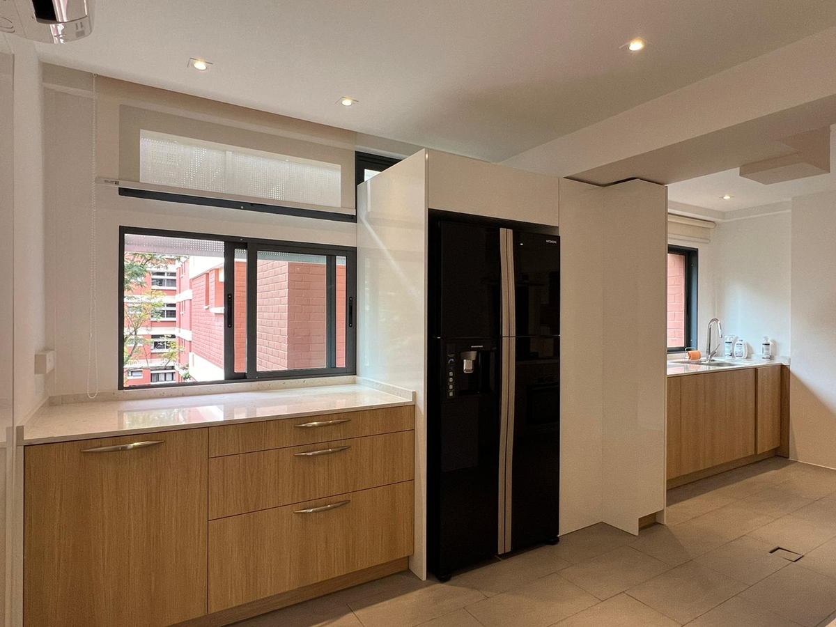 Timber-look kitchen cabinets along the window, beside a black refrigerator.