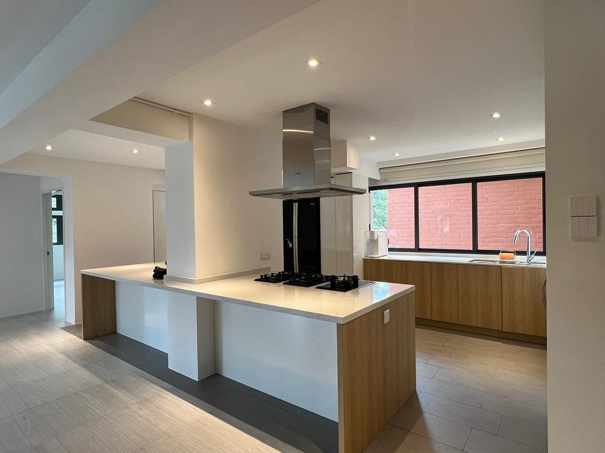 An island kitchen with a suspended stainless hood, timber-look cabinets and windows beyond.