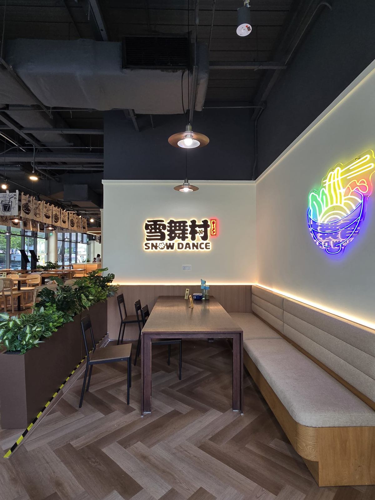 转角的卡座与餐桌，墙上是霓虹灯，头顶是吊灯。